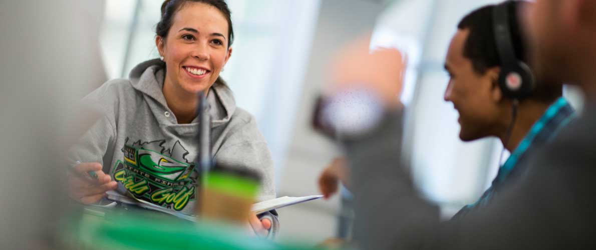 One student with a gray hoodie speaking to multiple other students